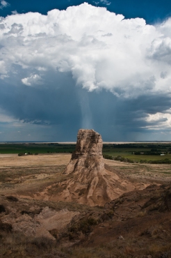 Narrow rain squall falling behind Jail Rock viewed from Courthouse Rock. Both Jail and Courthouse Rocks were important landmarks along the Oregon Trail, Nebraska.